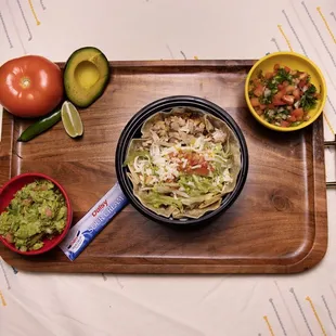 a bowl of mexican food on a wooden tray