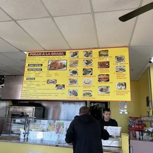 a man standing in front of a menu board
