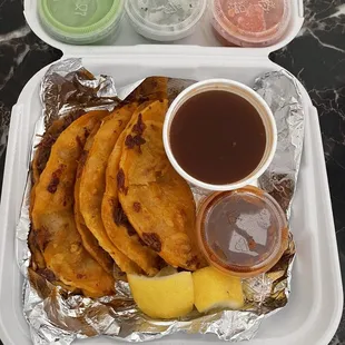 Birria Tacos with lemons, salsa, onions and cilantro, etc
