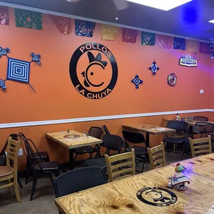 Interior distinctive wooden tables with a decorative wall with the logo of Pollos LaChuya
