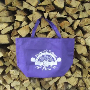 a purple tote bag on a pile of wood