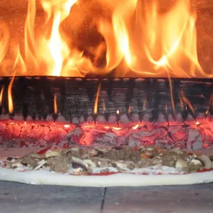 a pizza being cooked in a brick oven