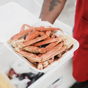 a person holding a tray of crab legs