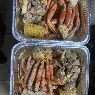 two trays of crab legs and corn on the cob