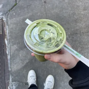 a person holding a green drink