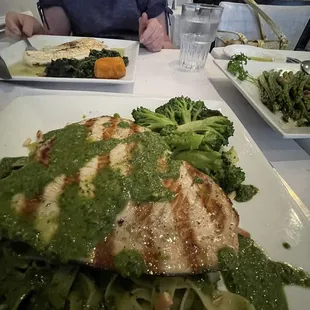 Swordfish with a drizzle of pesto sauce over fettuccini