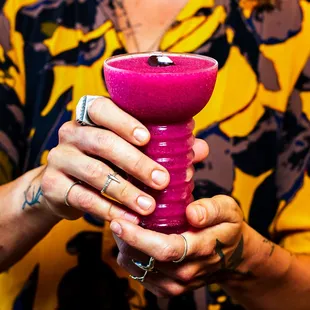 a woman holding a pink drink
