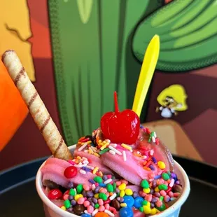 a cup of ice cream with sprinkles and a cherry on top