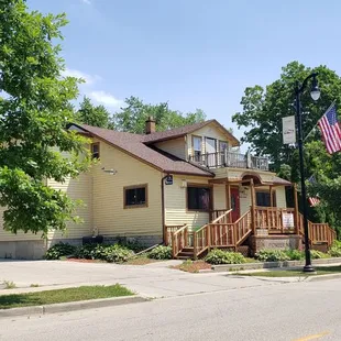 a yellow house with a flag on the front porch
