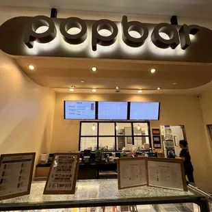 the inside of a restaurant with a sign above the counter