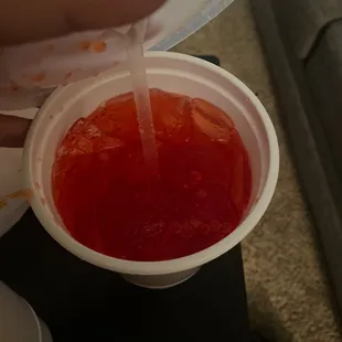 a person pouring ketchup into a cup