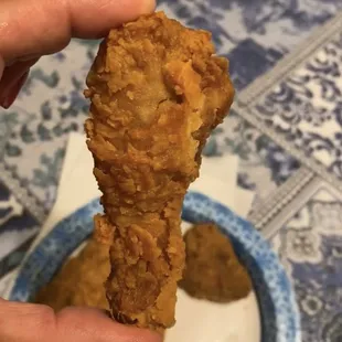 a hand holding a piece of fried chicken