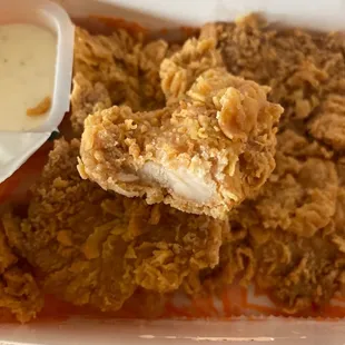 a plate of fried chicken with a side of dipping sauce