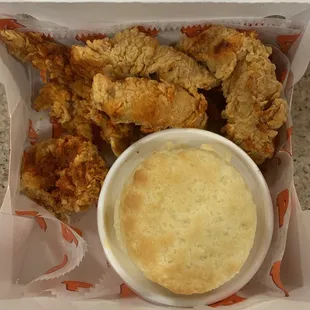 a basket of fried chicken with a side of dip