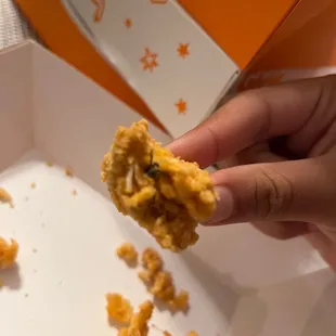 a hand holding a piece of fried chicken