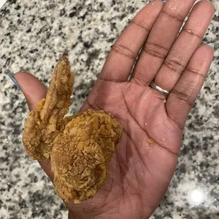 a hand holding a fried chicken