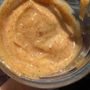 a hand holding a bowl of peanut butter