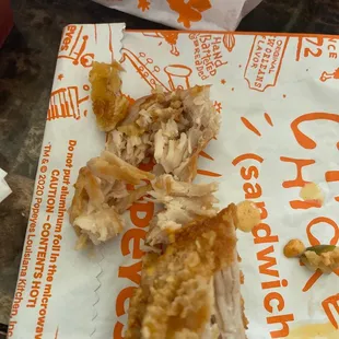 a half eaten chicken sandwich on a paper bag