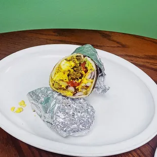 a burrito wrapped in foil on a plate