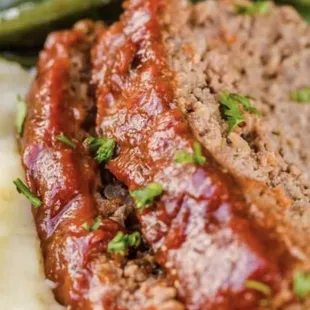 a plate of meatloaf with mashed potatoes and green beans