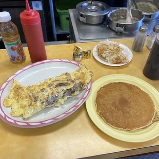 Steak Omelette, a single pancake, and shredded hash browns with an apple juice.