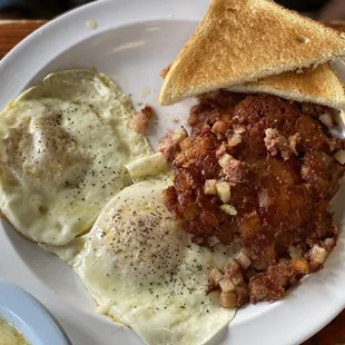 Two eggs over easy, corned beef hash, grits and toast