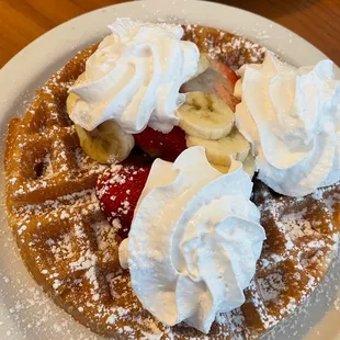 a waffle topped with whipped cream and fruit
