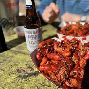 a plate of crawfish and a bottle of beer