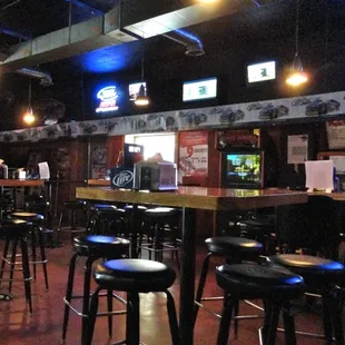 a bar with stools and televisions