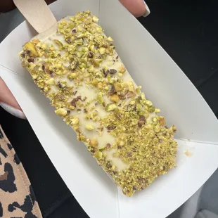 a person holding a pops bar with pistachios and nuts