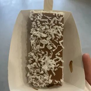 Coconut popsicle, dipped in milk chocolate, with coconut shavings