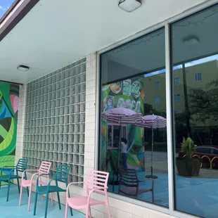 the outside of a building with colorful chairs and tables