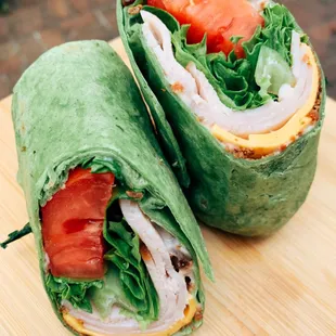 a wrap with chicken, lettuce, tomato, and cheese