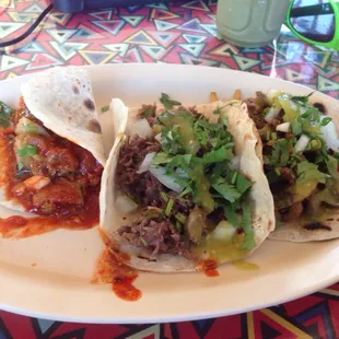 Three tacos the best you can find, barbacoa, pork, fajita, cilantro and onions.