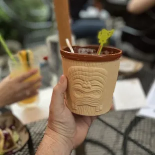 a hand holding a tiki cup