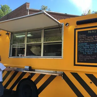 two men standing outside of a food truck