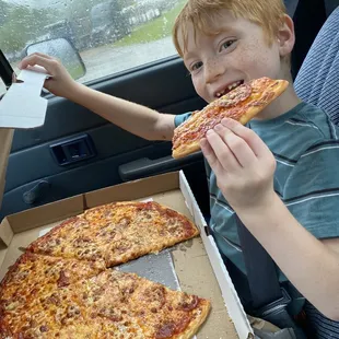 a boy eating a slice of pizza