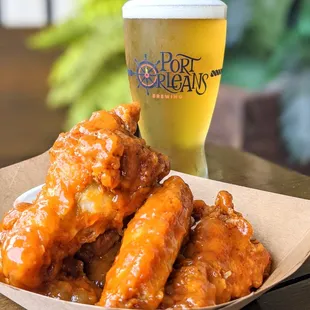 a basket of chicken wings and a glass of beer