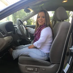 Anna is sitting comfortably away from steering wheel, her legs are supported by the seat
