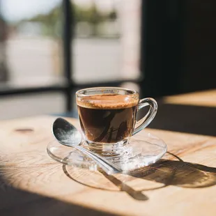 a cup of coffee on a saucer with a spoon