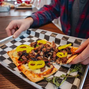 a person taking a slice of pizza