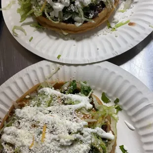 Sopes with choice of meat and beans. topped with cilantro, onions, lettuce, sour cream and red salsa