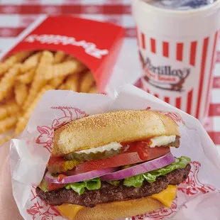 a hand holding a cheeseburger and fries