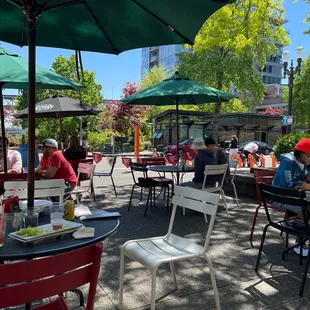 people sitting at tables under umbrellas