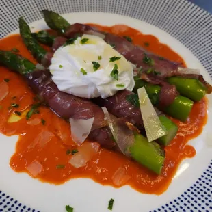 Prosciutto wrapped asparagus with poached fresh egg and red pepper sauce. Mascarpone and lobster fritters in lobster sauce