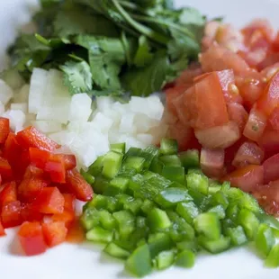a plate of chopped tomatoes, chopped onions, and chopped green peppers