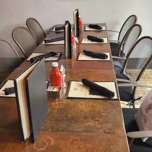 a long wooden table with chairs and a painting on the wall