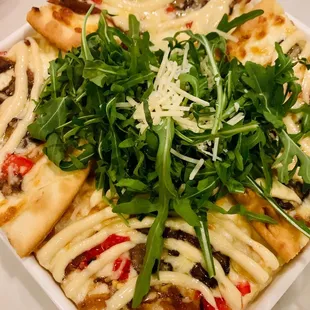 a plate of pizza with greens on top