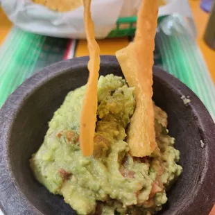a bowl of guacamole and tortillas