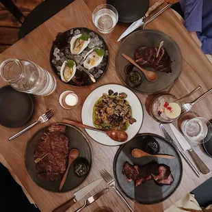 a wooden table with plates of food and utensils